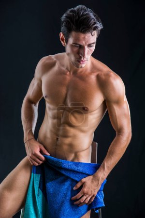 Porträt eines nackten, gut aussehenden jungen Mannes mit schmachtendem Blick, der den Schritt mit einem Handtuch oder T-Shirt bedeckt
