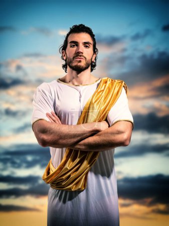 Photo for Ancient god looking at camera with arms crossed on his chest, against blue cloudy sky - Royalty Free Image