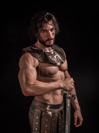 Jeune homme musclé posant torse nu en costume de gladiateur romain ou spartiate en studio