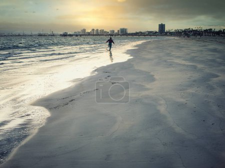 Téléchargez les photos : Une personne marchant sur une plage près de l'océan. Photo d'une personne profitant d'une promenade paisible le long des superbes plages de Los Angeles, Californie - en image libre de droit