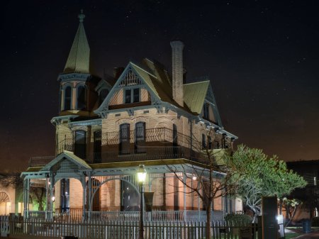 An old victorian house lit up at night. Photo of a beautifully illuminated Victorian house at night