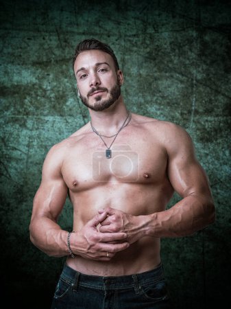 A shirtless man posing for a picture. Photo of a muscular man posing shirtless for a photo in front of green background