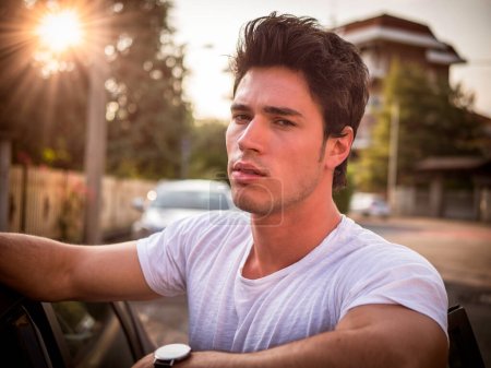 Téléchargez les photos : Un homme en chemise blanche penché par la fenêtre d'une voiture - en image libre de droit