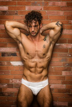 Photo for A man in a white underwear posing for a picture. Photo of a confident man in white underwear striking a pose for a photoshoot in front of a brick wall - Royalty Free Image