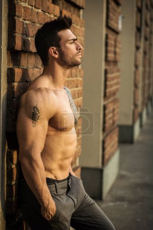 Photo for A shirtless man leaning against a brick wall - Royalty Free Image