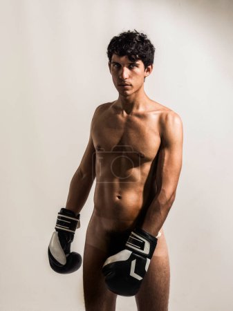 Ein völlig nackter junger, athletischer Mann ohne Hemd und Boxhandschuhe. Ein hübscher, athletischer junger Mann