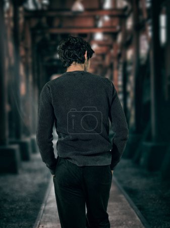 Photo for A man walking down a dark alley way, unrecognizable, with hands in his pockets - Royalty Free Image