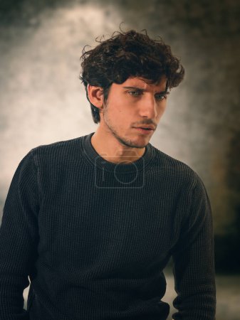 Foto de Un hombre en un suéter negro está posando con una expresión atormentada, preocupada, mirando aodwn - Imagen libre de derechos
