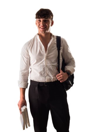 Foto de Un joven atractivo con camisa blanca y pantalones negros, un estudiante sonriente con mochila y libros en una mano - Imagen libre de derechos