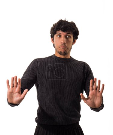 Un hombre vistiendo un suéter negro está de pie y extendiendo sus manos hacia afuera en un gesto sencillo.