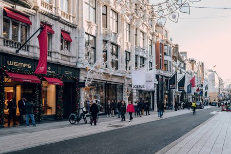 Photo for London, UK - December 26, 2022: People walking past the high end stores on New Bond Street, one of the most famous streets for luxury shopping in London. - Royalty Free Image