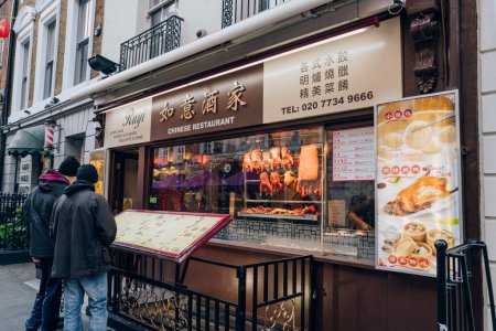 Téléchargez les photos : Londres, Royaume-Uni - 26 décembre 2022 : Façade du restaurant Ruyi à Chinatown, Londres, les hommes regardent le menu à l'extérieur. Chinatown abrite une grande communauté d'Asie de l'Est et est célèbre pour ses restaurants et événements. - en image libre de droit