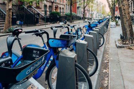 Foto de Nueva York, Estados Unidos - 22 de noviembre de 2022: Cierre de fila de Citi Bikes estacionadas en los muelles de una calle en Manhattan, Nueva York. Citi Bike es un sistema público privado para compartir bicicletas que sirve a la ciudad. - Imagen libre de derechos