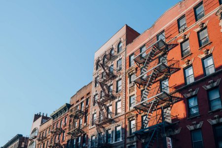 Foto de New York, USA - November 22, 2022: Row of typical New York apartment blocks with fire escape in Nolita, a charming and upscale area of Manhattan famous for its shops and restaurants. - Imagen libre de derechos