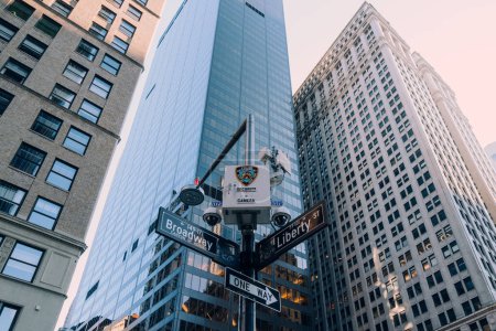 Téléchargez les photos : New York, États-Unis - 25 novembre 2022 : Caméra de la police de New York au-dessus des panneaux de nom de rue au coin de Broadway et Liberty st., l'une des 15 000 caméras de surveillance de la police de New York à Manhattan, Brooklyn et le Bronx. - en image libre de droit