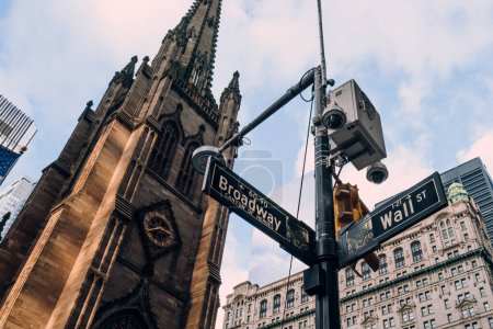 Foto de New York, USA - November 25, 2022: NYPD camera above street name signs on the corner of Broadway and Wall Streets., one of over 15,000 NYPD surveillance cameras in Manhattan, Brooklyn and the Bronx. - Imagen libre de derechos