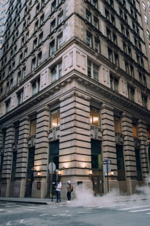 Foto de Nueva York, Estados Unidos - 25 de noviembre de 2022: Vapor se levanta de un respiradero en una calle del Distrito Financiero, el corazón financiero de Nueva York y el hogar de Wall Street. - Imagen libre de derechos
