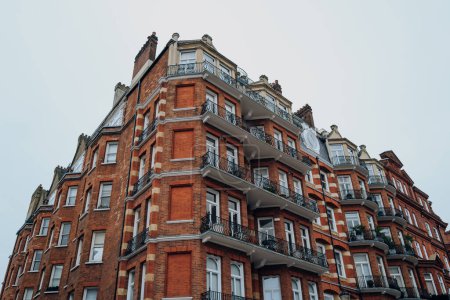 Foto de Vista de ángulo bajo de un bloque de apartamentos tradicional de ladrillo rojo con marcos de ventanas blancas y balcones en Kensington y Chelsea, Londres, Reino Unido. - Imagen libre de derechos