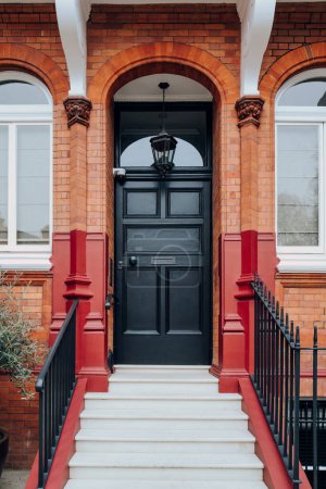 Schwarze Haustür eines traditionellen Hauses in Kensington und Chelsea, West London, Großbritannien.