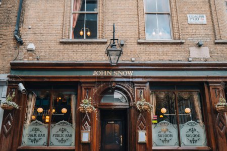 Foto de Londres, Reino Unido - 13 de abril de 2023: Fachada y entrada de John Snow, un bar de salón de madera oscura en Londres que sirve cervezas de Yorkshire, llamado así por el médico que rastreó el brote de cólera en Londres. - Imagen libre de derechos