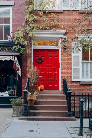 Téléchargez les photos : 23 novembre 2022 - New York, États-Unis : Porte d'entrée rouge vif sur une maison à West Village, un quartier de Manhattan avec une atmosphère résidentielle à l'ancienne. - en image libre de droit