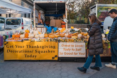 Photo for November 23, 2022 - New York, USA: Pumpkins and squashes at Grow NYC Union Square Greenmarket, a year-round farmers market with various farm and small batch food producers, people walk past. - Royalty Free Image