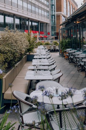 Foto de Londres, Reino Unido - 06 de julio de 2023: Mesas al aire libre del restaurante Cote Brasserie en St Katharine Docks, un antiguo muelle y ahora un distrito mixto y el único puerto deportivo de Londres en el centro de Londres. - Imagen libre de derechos