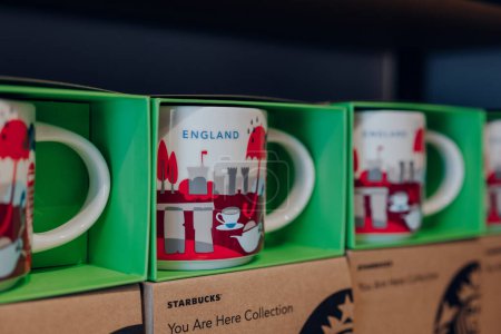 Téléchargez les photos : Londres, Royaume-Uni - Juillet 06, 2023 : Tasses Angleterre à collectionner de vous êtes ici collection en vente à l'intérieur Starbucks café à Londres. Starbucks est une célèbre chaîne de cafés américains. - en image libre de droit