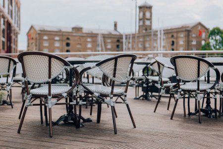 Téléchargez les photos : Tables et chaises de restaurant en plein air vides à St Katherine Dock à Londres, Royaume-Uni, objectif sélectif. - en image libre de droit