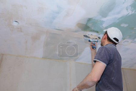 Photo for Worker make repairs in new apartment. Man plaster walls and ceilings. High quality photo - Royalty Free Image