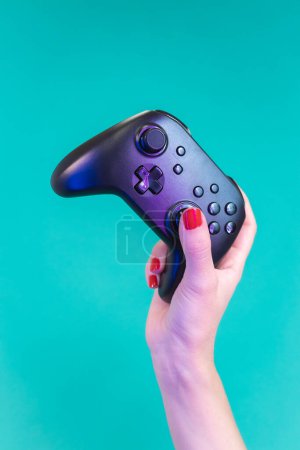 Photo for Woman hand holding joystick gamepad on blue background in neon studio light, close-up. Video gaming leisure addictive competition concept. Vertical high quality photo - Royalty Free Image