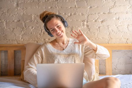 Woman in headphones having virtual meeting waving hand chatting video call with teacher on computer, studying on online courses or taking private lesson, remote student, High quality photo