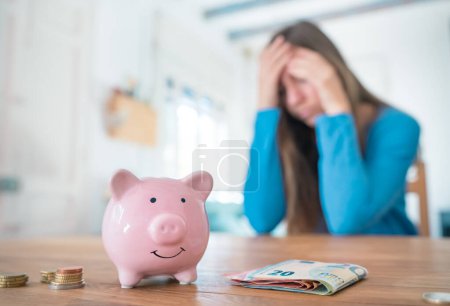 Téléchargez les photos : Woman with pink piggy bank worry and sad about money and household finances. Family savings and home economy - en image libre de droit