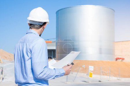 Photo for Unrecognizable civil engineer inspecting work with licenses and blueprints, standing outdoors at construction site. Inspector work control. Copy space for text. High quality photo - Royalty Free Image