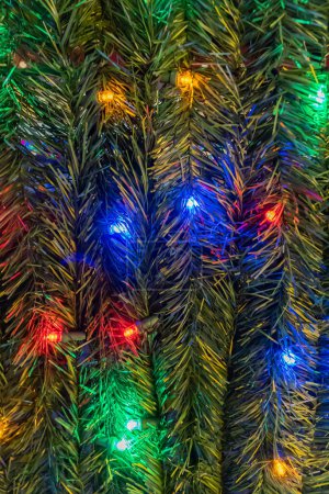 Photo for Close up background photograph of artificial green pine branches with colorful Christmas lights making a festive holiday backdrop. - Royalty Free Image