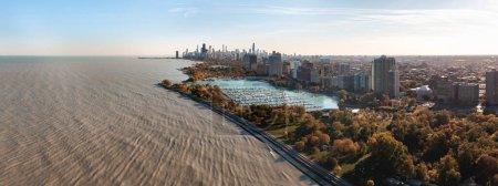 Téléchargez les photos : Aerial panorama above Lake Michigan overlooking Belmont harbor and the Lakeview neighborhood with the Chicago skyline in the distance on a sunny autumn day. - en image libre de droit