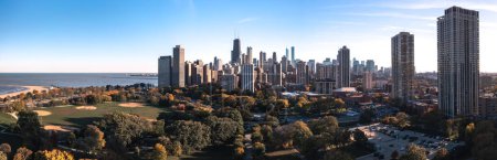 Téléchargez les photos : Chicago, IL - October 19th, 2022: The ball fields sit empty and quiet amongst a forest of autumn colored trees and high rise buildings casting shade over Lincoln Park on a blue sky afternoon. - en image libre de droit