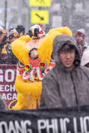 Téléchargez les photos : Chicago, IL - January 28th, 2023: A  bright yellow and orange lion dancer makes its way through the parade route with crowds of students marching in the annual Lunar New Year event and celebration. - en image libre de droit
