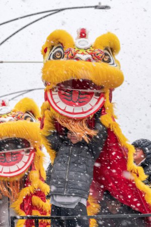 Téléchargez les photos : Chicago, IL - 28 janvier 2023 : Les danseurs de dragon lèvent leur costume haut dans les airs alors que la neige remplit le ciel lors du défilé annuel du Nouvel An lunaire Argyle. - en image libre de droit