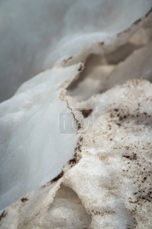 Photo for Close up of a delicate thin rippled white snowy ridge with sand and dirt formed from melting snow and ice along the lakefront of Lake Michigan on a sunny day making a great winter background. - Royalty Free Image