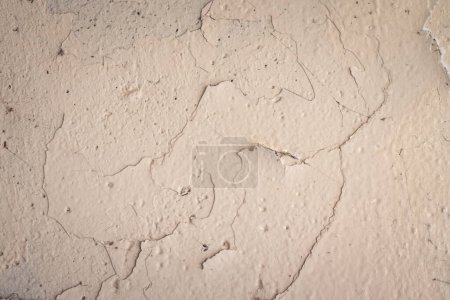 Téléchargez les photos : Gros plan de couches de peinture beige ou blanc cassé se détériorant, se fissurant et se décollant d'un mur en béton texturé, ce qui en fait une excellente image de fond. - en image libre de droit
