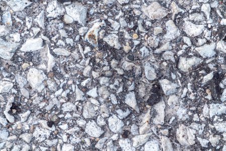 Téléchargez les photos : Macro photographie de surface de pavage d'asphalte à dessus noir altérée avec des pierres blanches montrant à travers la réalisation d'une grande image de fond industriel texturé avec espace de copie. - en image libre de droit