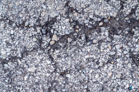 Téléchargez les photos : Macro photographie de surface de pavage d'asphalte à dessus noir altérée avec des pierres et des fissures, ce qui en fait une grande image de fond industriel texturé avec espace de copie. - en image libre de droit