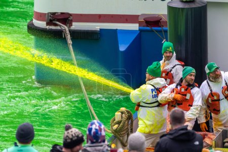 Téléchargez les photos : Chicago, IL - 11 mars 2023 : Les membres du syndicat local des plombiers 130 recouverts d'eau verte teintée d'orange rouille provenant d'un bateau de tourisme riverain lors de l'événement annuel de la Saint-Paddy. - en image libre de droit