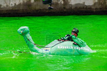 Photo for Chicago, IL - March 11th, 2023: A man dressed as a leprechaun rides inside the Kayak Chicago's loch ness monster boat in the bright green water from the annual St. Patrick's day event and festivities. - Royalty Free Image