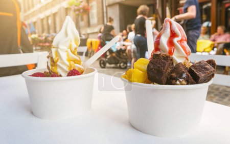 Téléchargez les photos : Deux tasses de yaourts glacés avec brownie et garnitures de fruits sur une table de restaurant - en image libre de droit