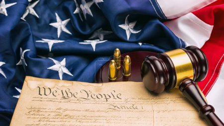 Foto de Constitución Americana con martillo de juez y cartuchos de pistola en una bandera de América - Imagen libre de derechos