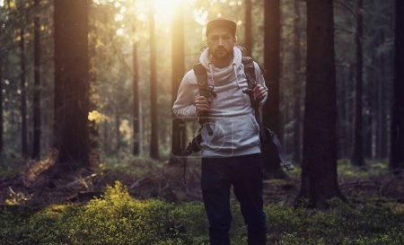 Téléchargez les photos : Portrait d'un jeune randonneur avec sac à dos dans la forêt lors d'une journée d'été - en image libre de droit