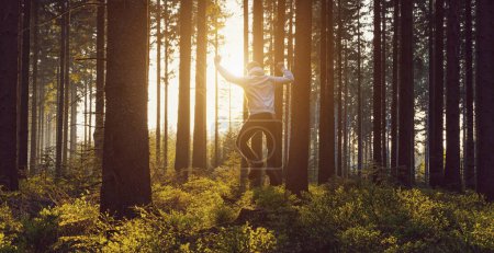 Téléchargez les photos : Jeune homme sautant dans la forêt au coucher du soleil - en image libre de droit