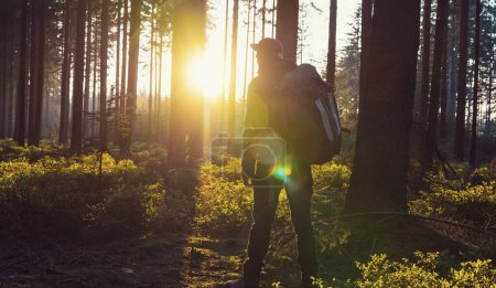 Téléchargez les photos : Randonneur avec sac à dos se détendre dans les bois et profite de la vue sur le coucher du soleil - en image libre de droit